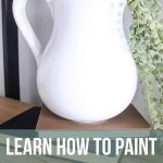 White pitcher with farmhouse style sitting on stack of vintage books on a wooden shelf