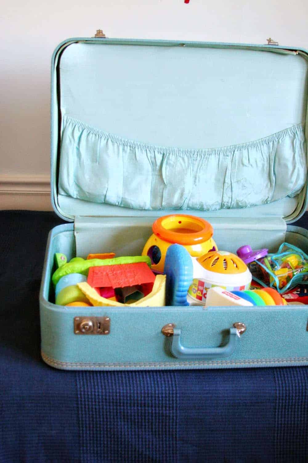 Blue vintage suitcase used as toy storage