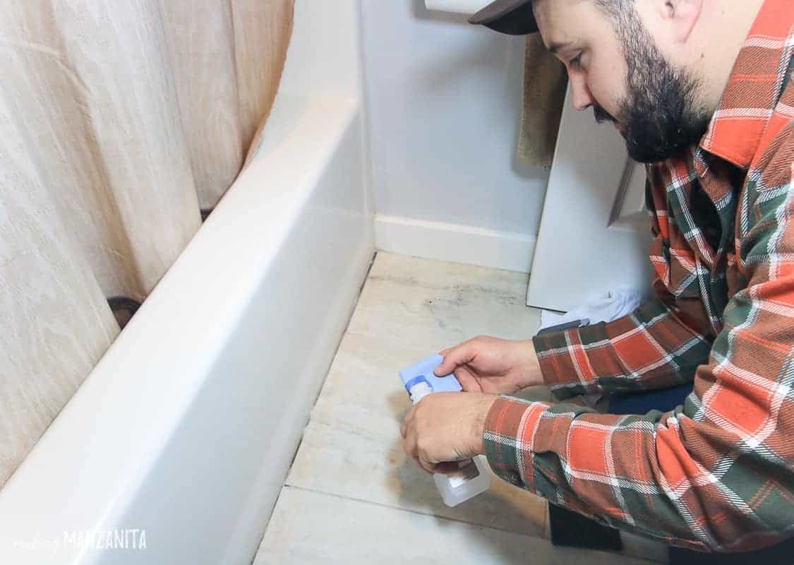 Using rubbing alcohol to clean the old caulk line on the bathroom floor