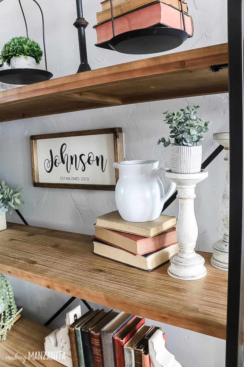 Decorating shelving ideas with farmhouse style decorations on a modern farmhouse shelving unit with antique books, candle stick holders, and metal scale