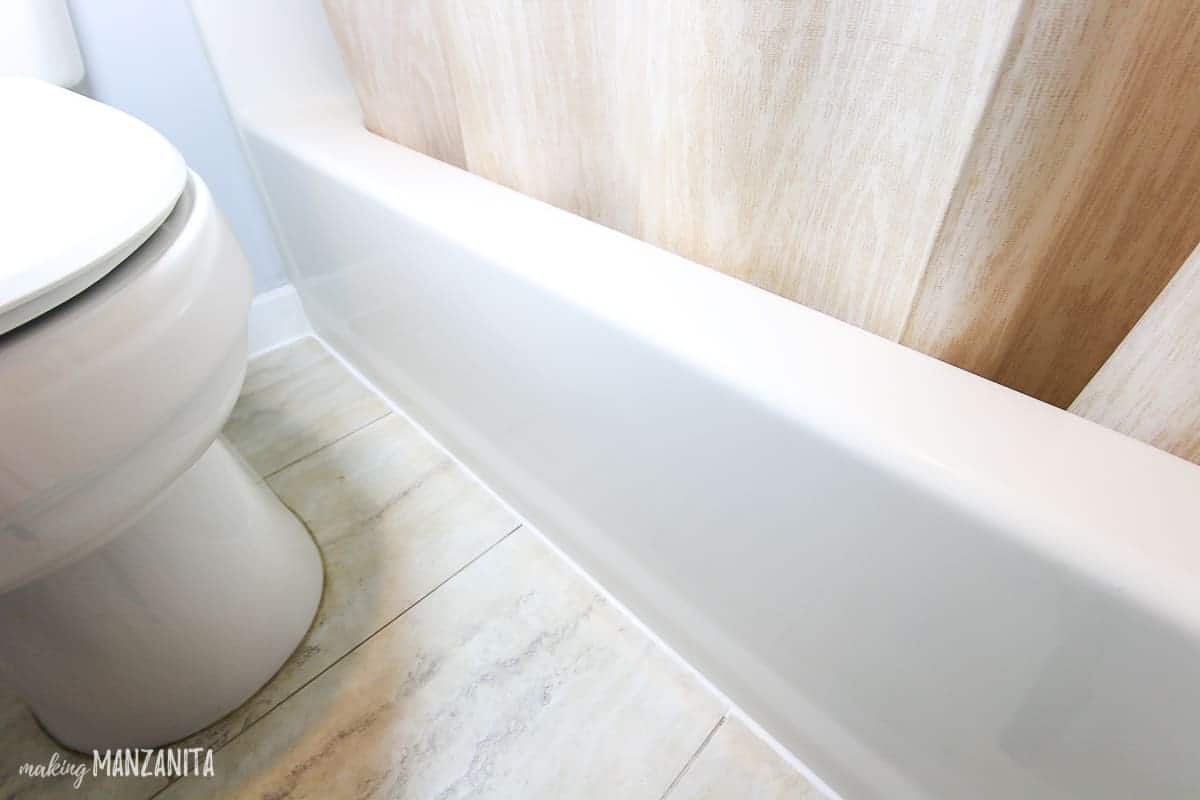 Fresh new white caulk lines in bathroom where the flooring meets the bathtub 