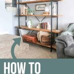 Side angle of a shelving unit in the corner of a living room decorated with farmhouse style like fixer upper with text overlay that says How to decorate shelves