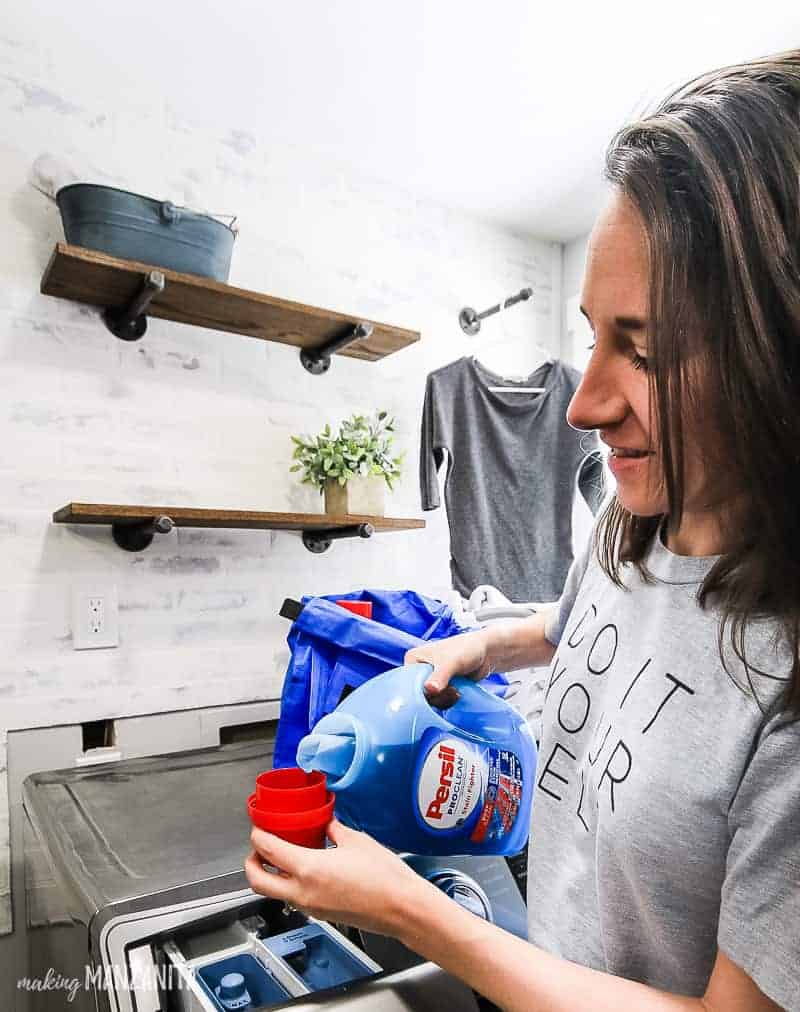 Woman pouring Persil laundry detergent into a cap to measure before pouring into washer drawer in farmhouse style laundry room