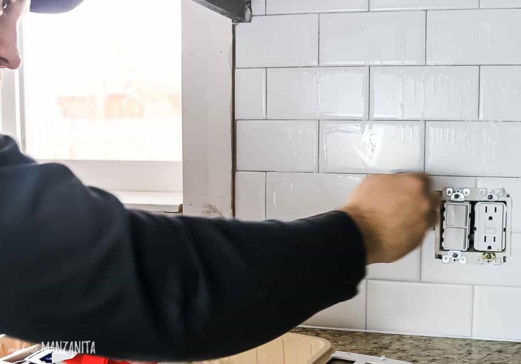 Sealing grout on subway tile backsplash with grout sealer and foam paint brush