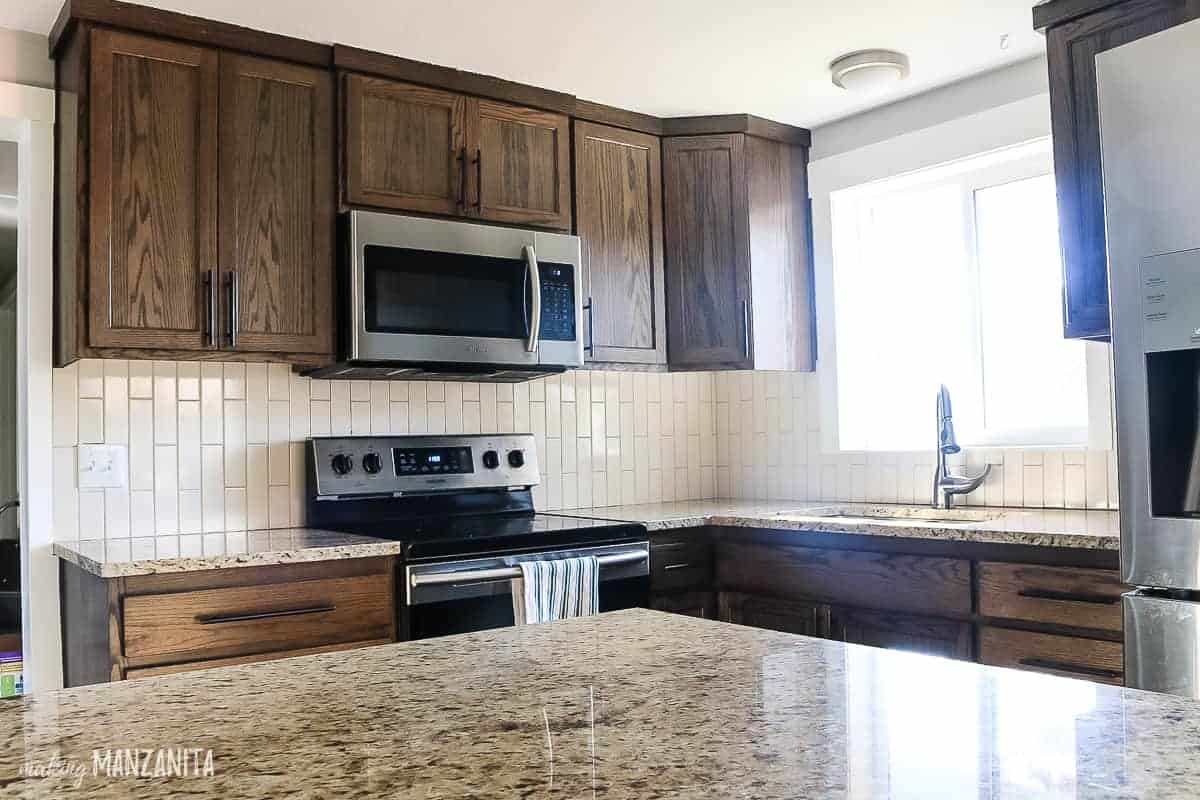 Before picture of a kitchen with dark cabinets, granite countertops, and a tan kitchen backsplash