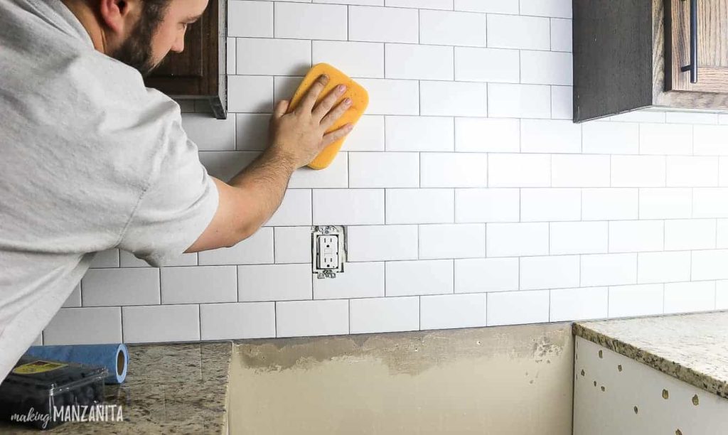 A photo shows that a man is cleaning the tiles on a wall.