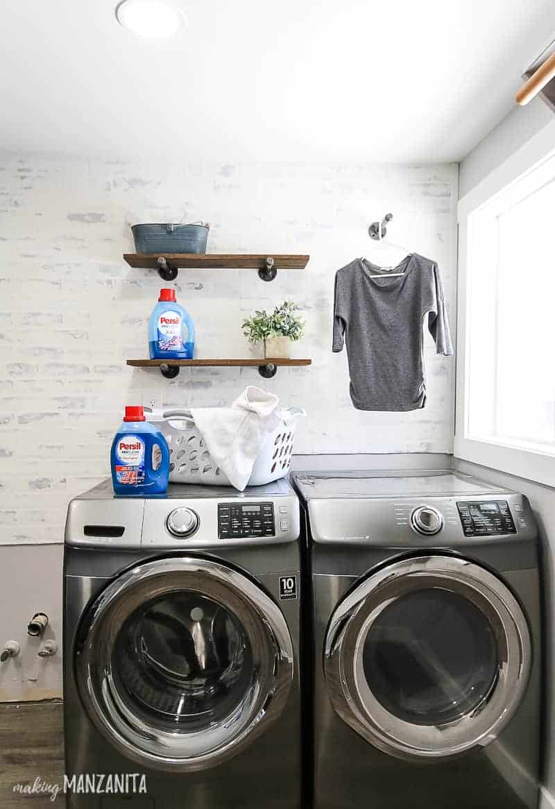 Farmhouse style laundry room makeover with side by side washer and dryer with a german schmear wall and floating shelves behind it