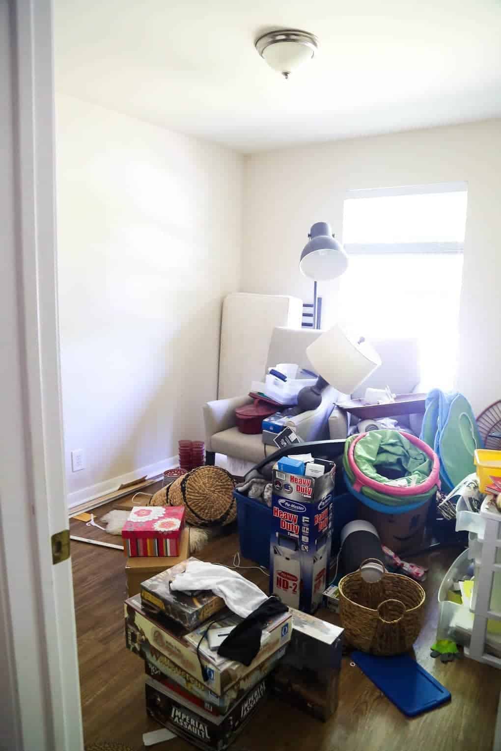 Bedroom with piles of junk, boxes and clutter before renovating into a beautiful nursery space