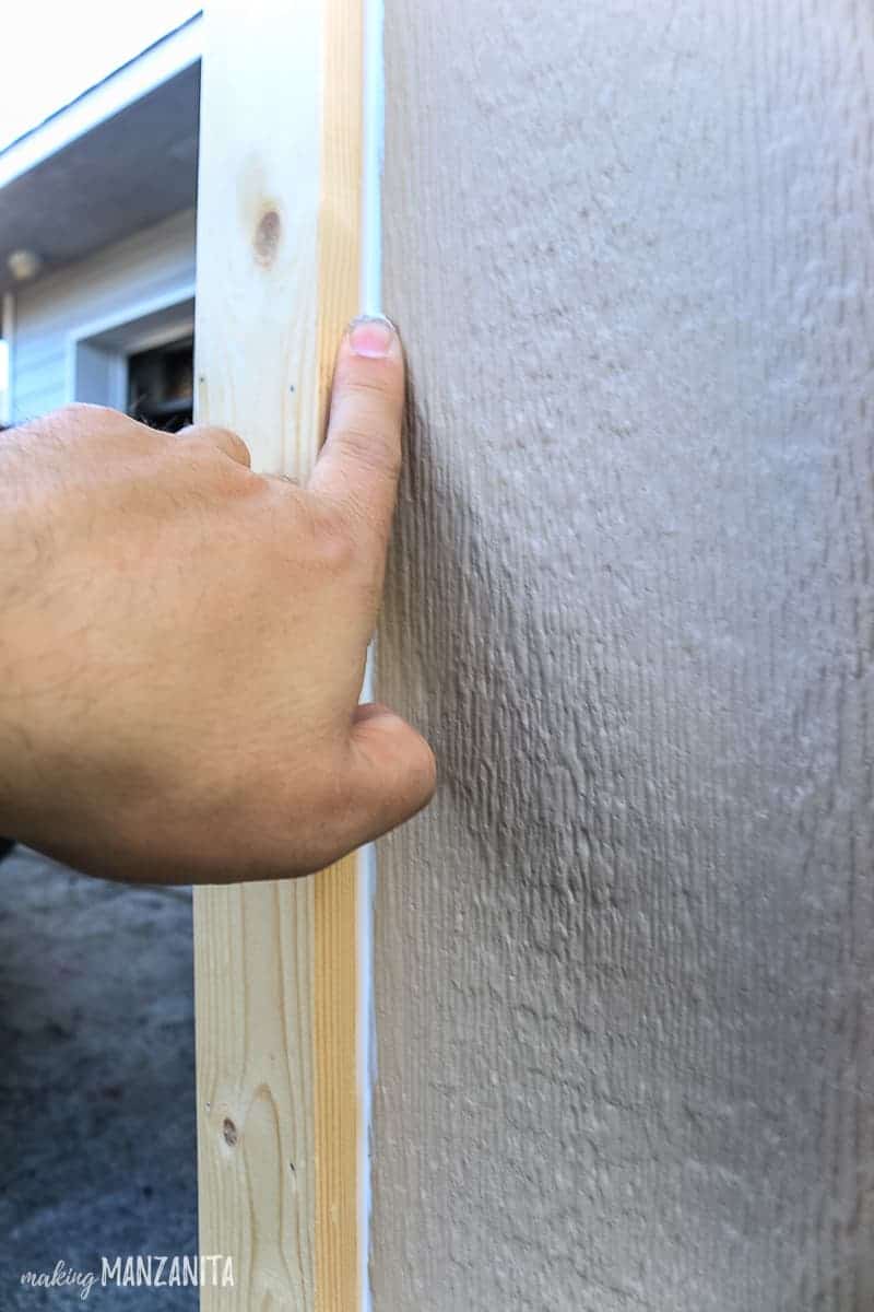 Man tooling bead of caulk on exterior porch post trim