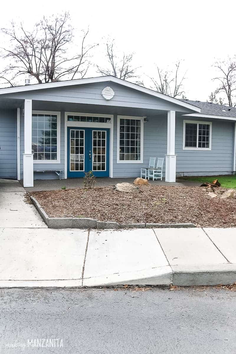 Front exterior of a ranch style house with front porch posts that are trimmed out with a farmhouse style and painted white. House is a light blue color