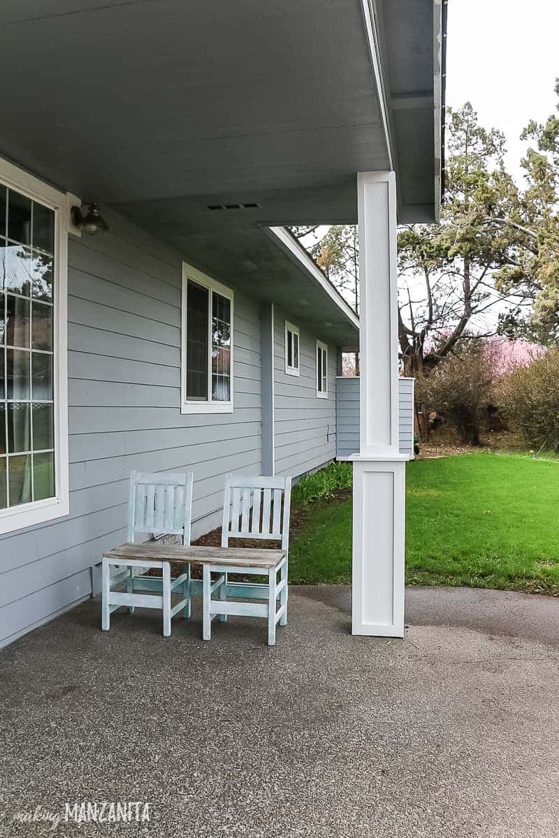 Side view of front yard and patio with new DIY porch posts with craftsman style trim added and an upcycled chair bench sitting on porch area with grass shown in background