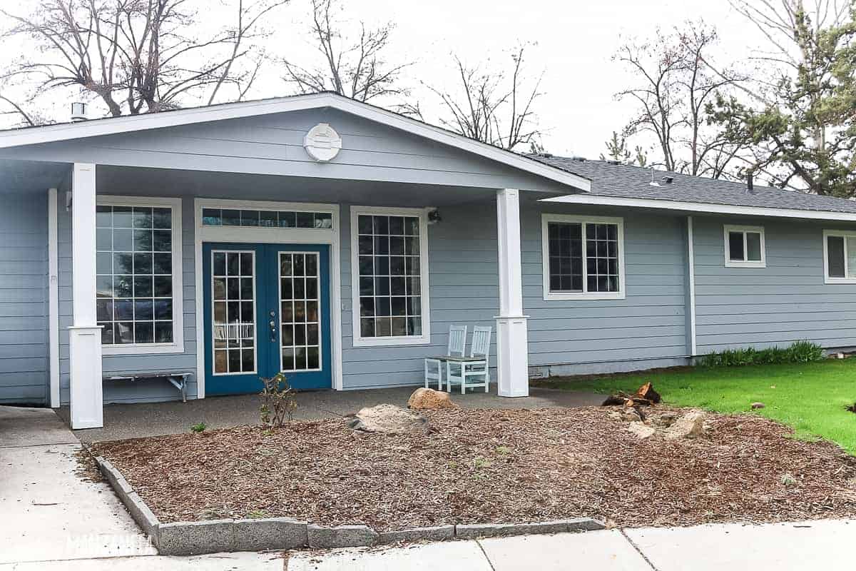 Front entry on a house that is painted baby blue with white trim and french doors for entry with white painted and beefed up porch posts 