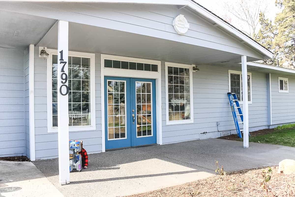 Front of house painted light blue with white trim that has a front porch with skinny white porch posts, french doors painted blue