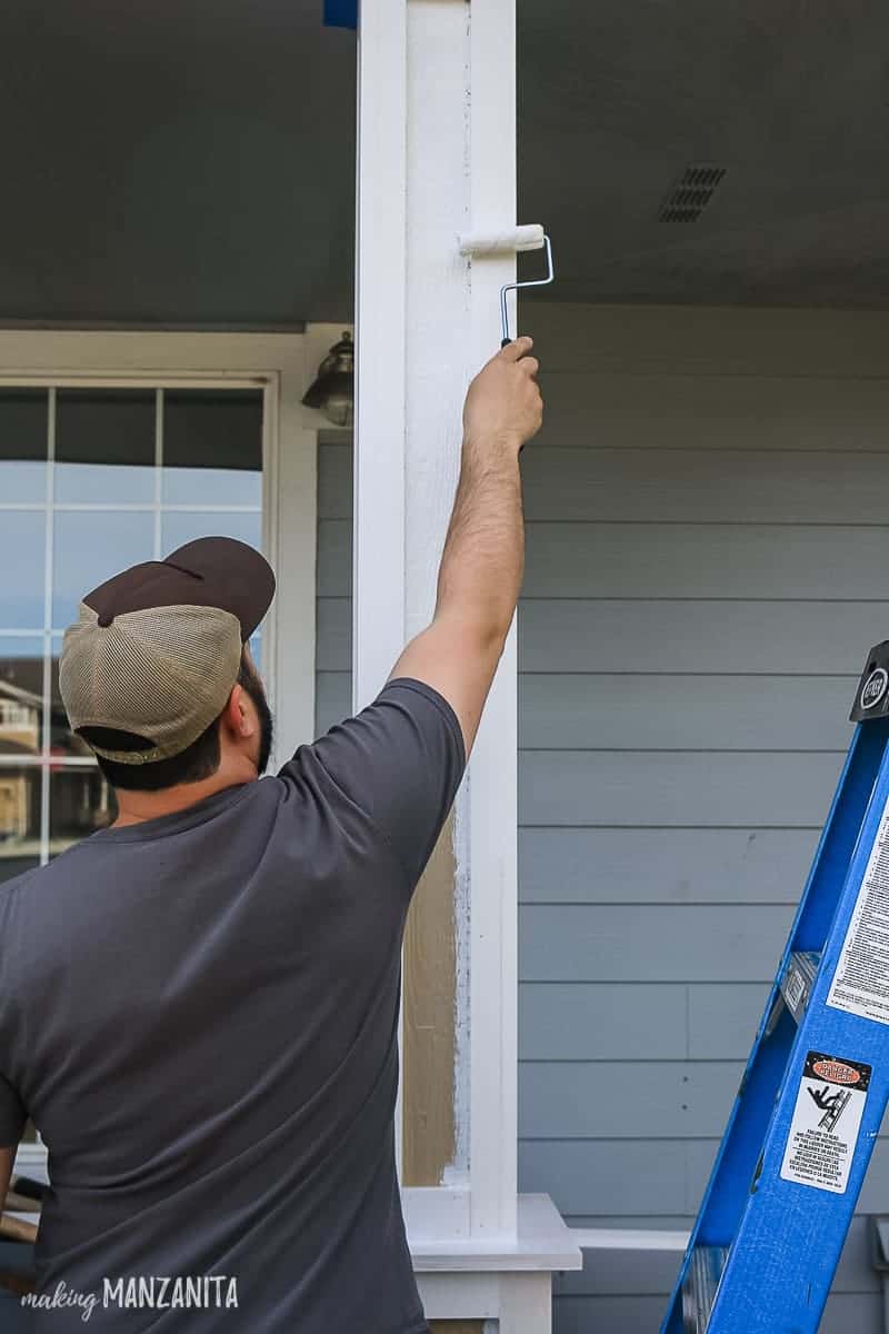 Man painting porch posts with white exterior paint to a new porch column with 4 inch roller 