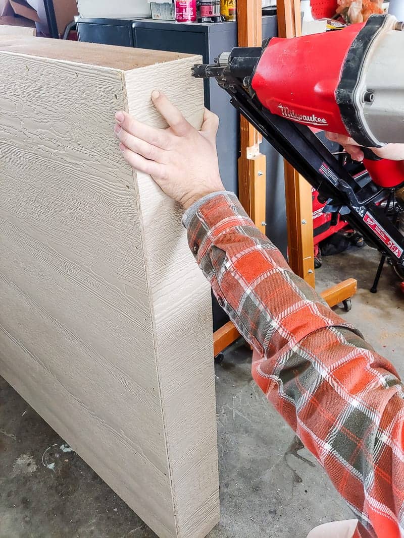 Using a nail gun to attach sheeting to the outside of the outdoor chalk board box frame.