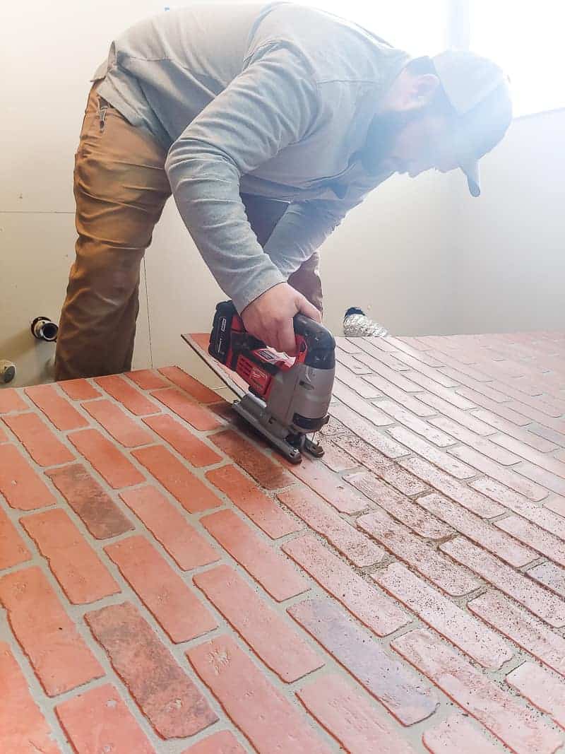 Man using jig saw to cut faux brick panels before installing on the wall