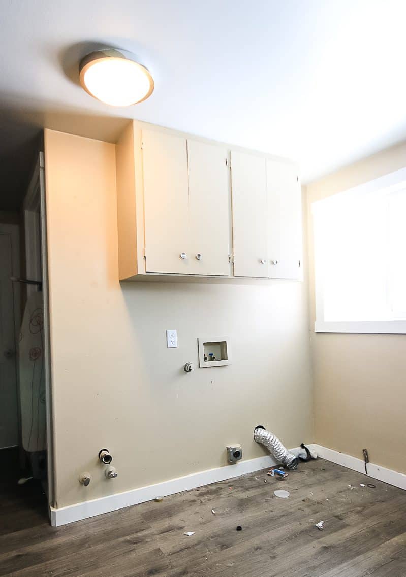 Tan painted walls in laundry room with washer and dryer removed and upper cabinet in place 