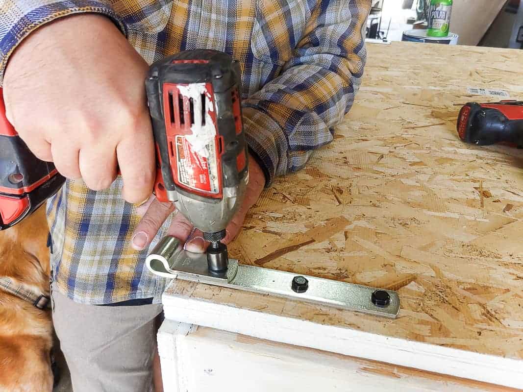 Attaching the hinge strap and lag bolts on the outdoor chalkboard storage box.