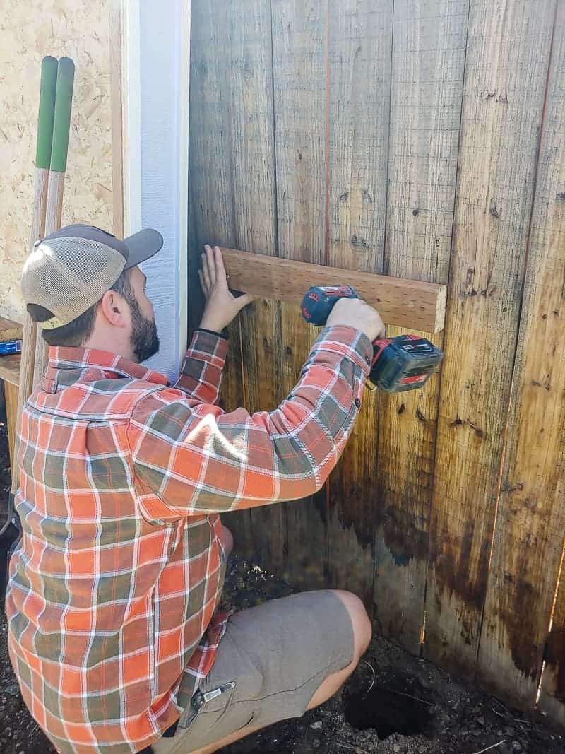 Attaching a support beam to the fence - this beam will help support the weight of the outdoor chalkboard and the wooden storage box.