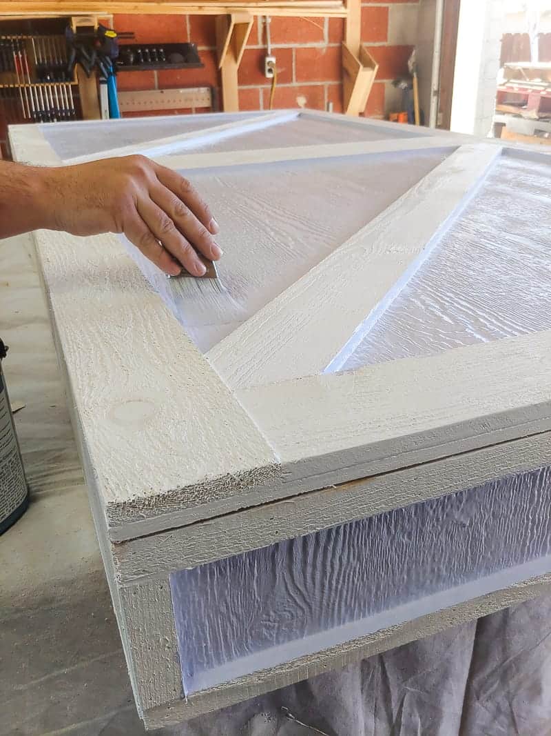 Using white exterior paint to paint the front of the outdoor chalkboard storage box.