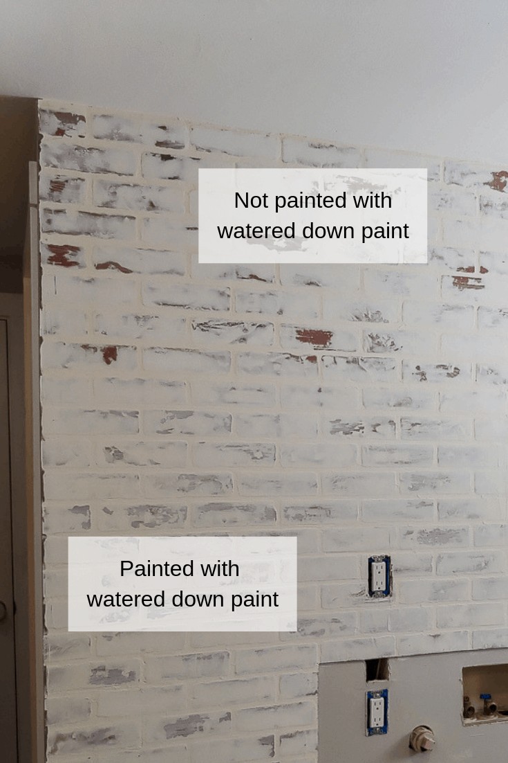 Fake brick wall with german schmear treatment using joint compound that turned orange-ish. Image shows the bottom part of the wall painted with watered down paint to lighten it up and seal the wall. The top portion shows the wall unpainted and unsealed.