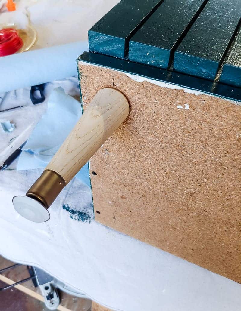 Wooden tapered furniture legs attached to the boho style laminate cabinet makeover.