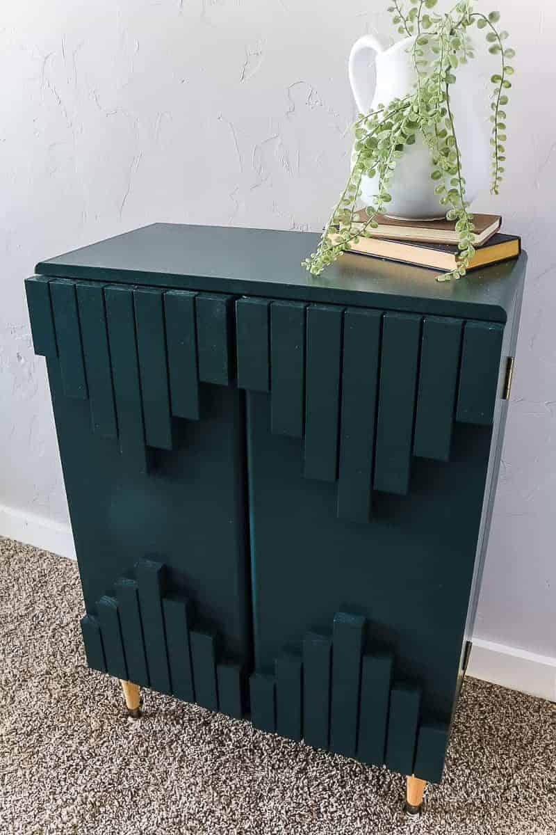 Finished dark green boho style laminate cabinet makeover with aztec pattern on front displayed with farmhouse home decor.