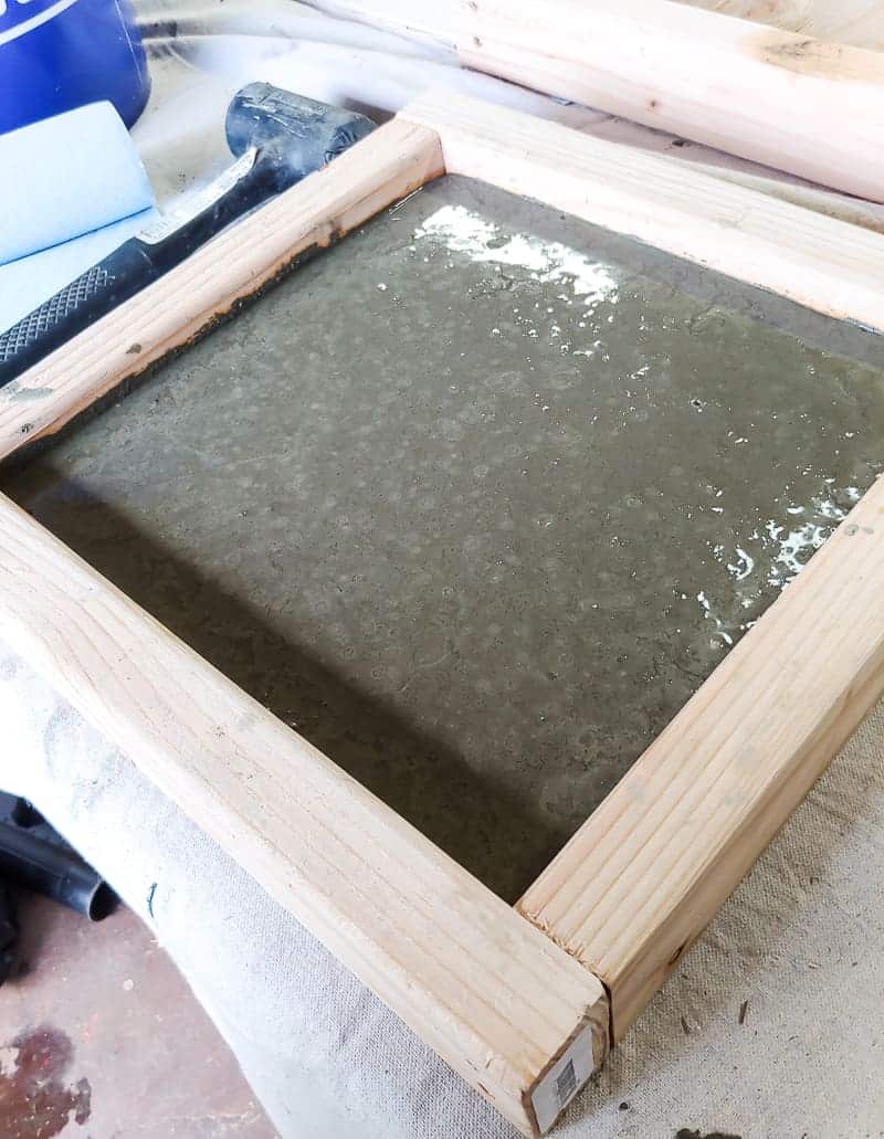 Concrete mix poured into the square wooden mold to create DIY concrete garden stepping stones