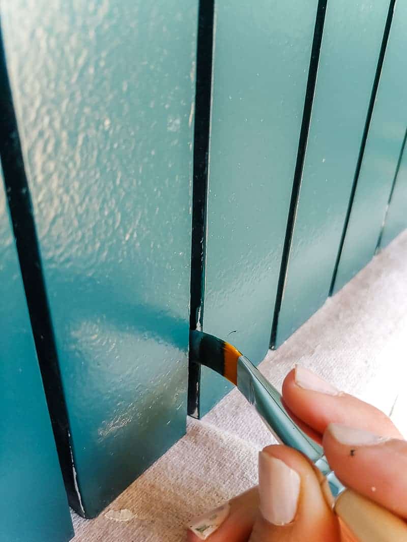 A laminate cabinet makeover painting the gaps of the trim pieces with small artist paint brush