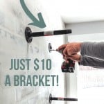 Attaching pipe along with other attached pipe lines on the wall with text overlay that says industrial shelves and Just $10 a Bracket