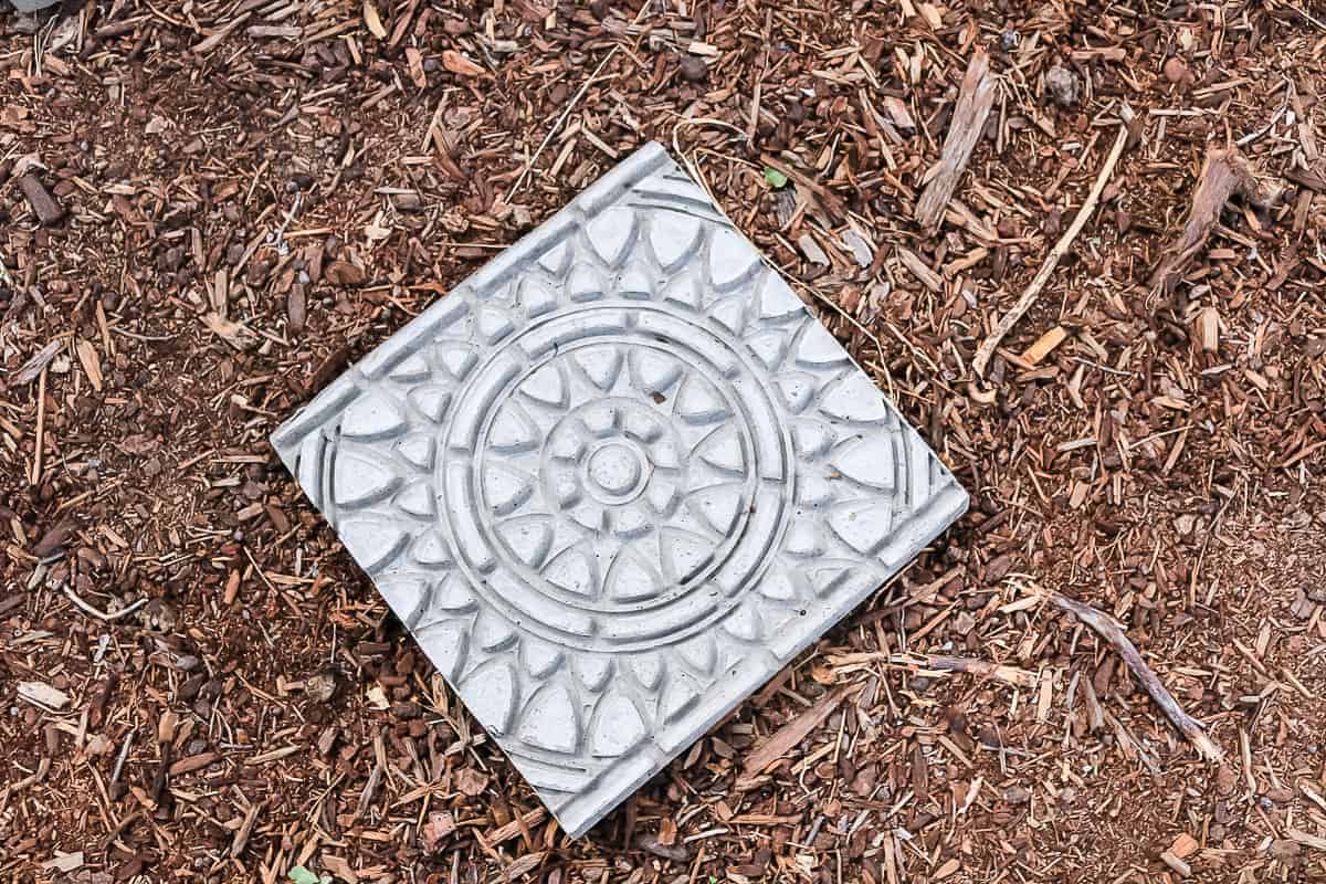 Finished DIY garden stepping stones laying on the ground of a garden, stamped with an intricate design