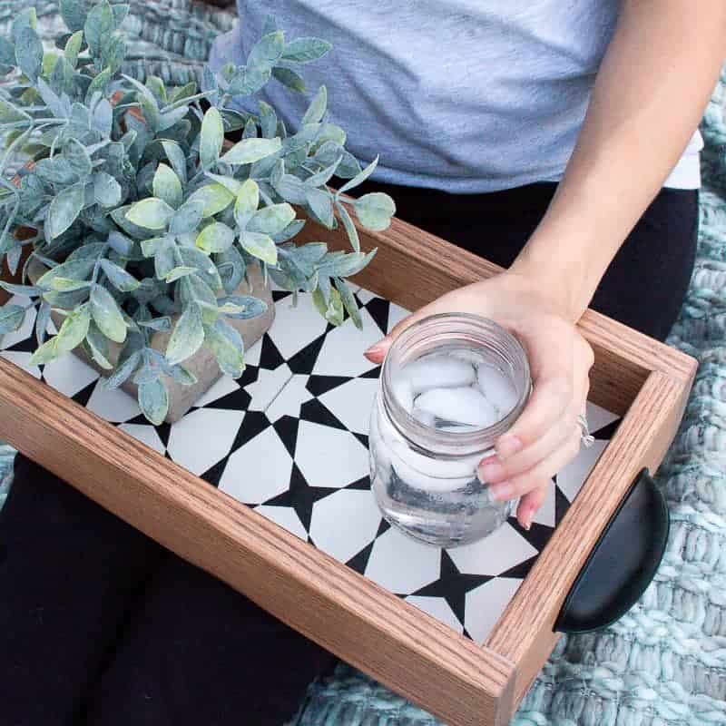 Woman holding the iced water on the diy serving tray beside the succulent in what to do with leftover tiles.