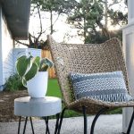 Photo of white planter on top of the DIY concrete side table beside the farmhouse chair and pillow on the porch with text overlay that says Make your Own concrete Side Table