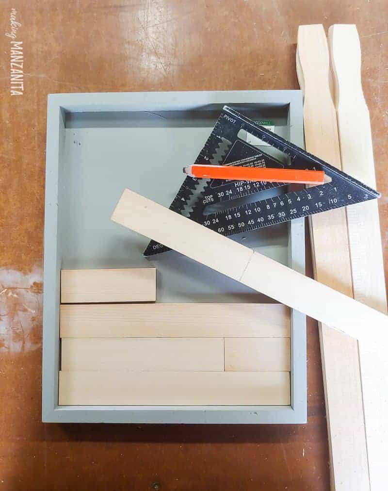 Measuring paint sticks to create a mini shiplap pattern in a wooden frame
