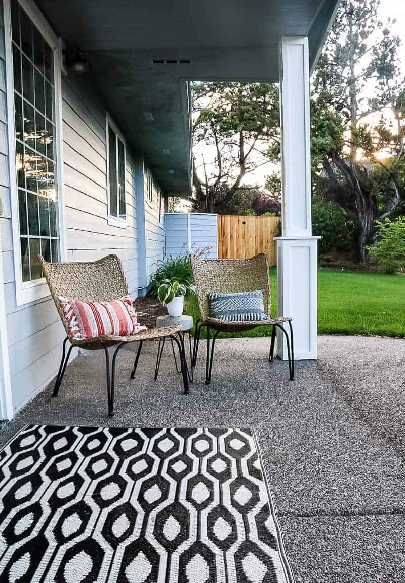 Our home's front porch - two wicker chairs with black hairpin legs and a diy concrete side table, between the two chairs.