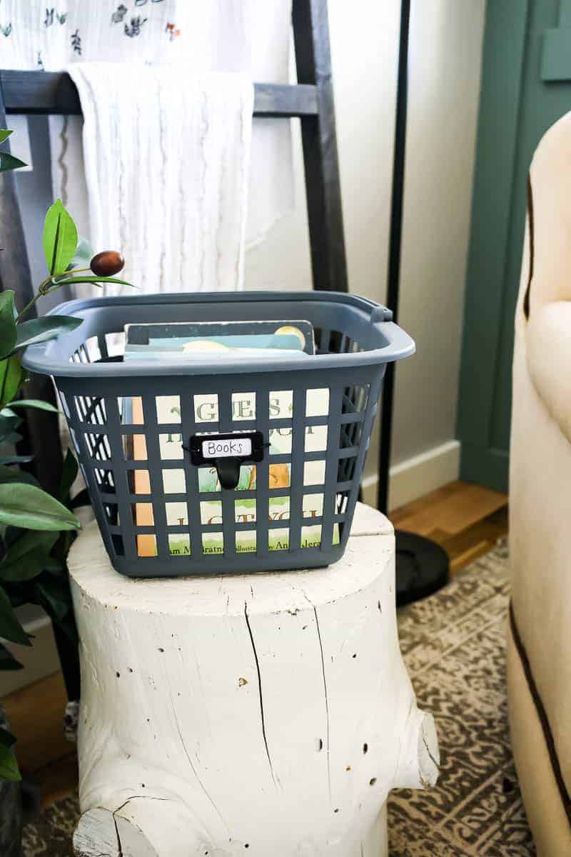 This DIY books basket was a Dollar Store craft and is perfect for added storage in our baby girl nursery. It sits atop a white painted tree stump end table.