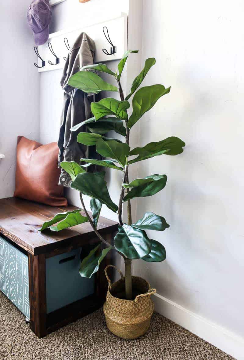 Coat racks, leather pillow, wooden bench, wooden shoe storage and indoor faux fiddle leaf fig tree in basket for the modern farmhouse entryway design