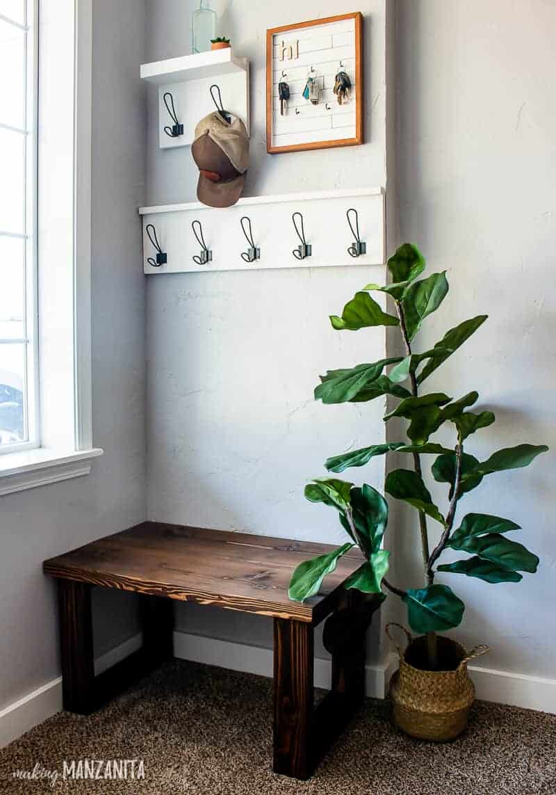 Small entryway showing the coat racks, DIY key holder, small entryway bench and an indoor plant.