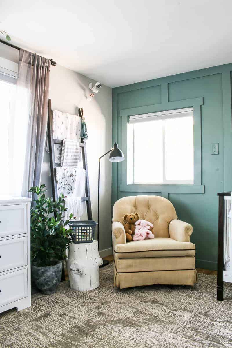 The nursing corner of our baby girl nursery is quiet and peaceful, with a comfortable vintage tan suede chair, a DIY baby blanket ladder, faux olive tree for a pop of fresh greenery, and a rustic style tree stump side table.