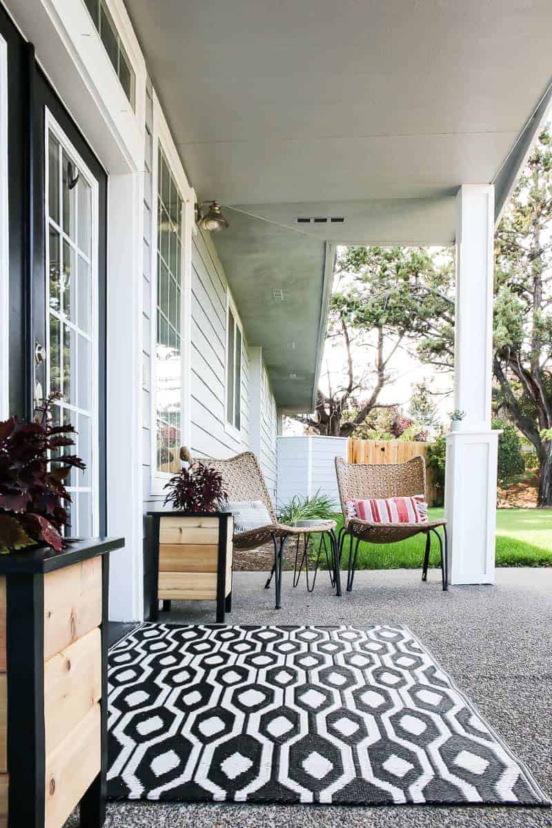 Our new front porch decor! Two diy planter boxes with made natural cedar and black wood frames, a black and white geometric rug, two wicker chairs and a DIY concrete side table, with matching hairpin legs.