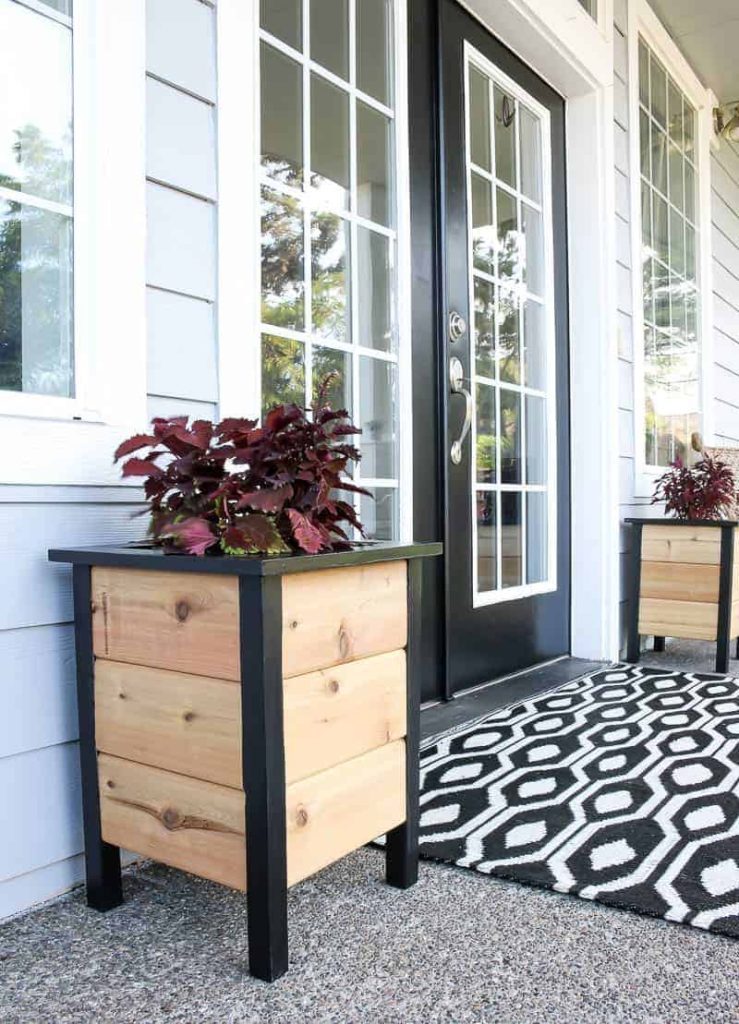 Behr Black paint color provides a great contrast on this front porch as the trim color on the wooden planter boxes and the paint color on the french doors 