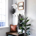 Entryway design which includes coat racks, key holder, leather pillow, wooden bench, wooden shoe storage and indoor plant with text overlay that says Small Entryway