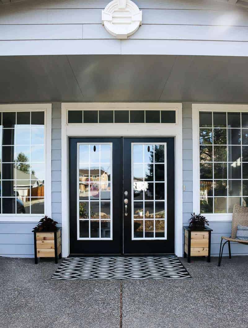 A look at the front porch of our home. Black-painted double doors framed by two DIY planter boxes made with natural cedar wood and black painted wood frames.