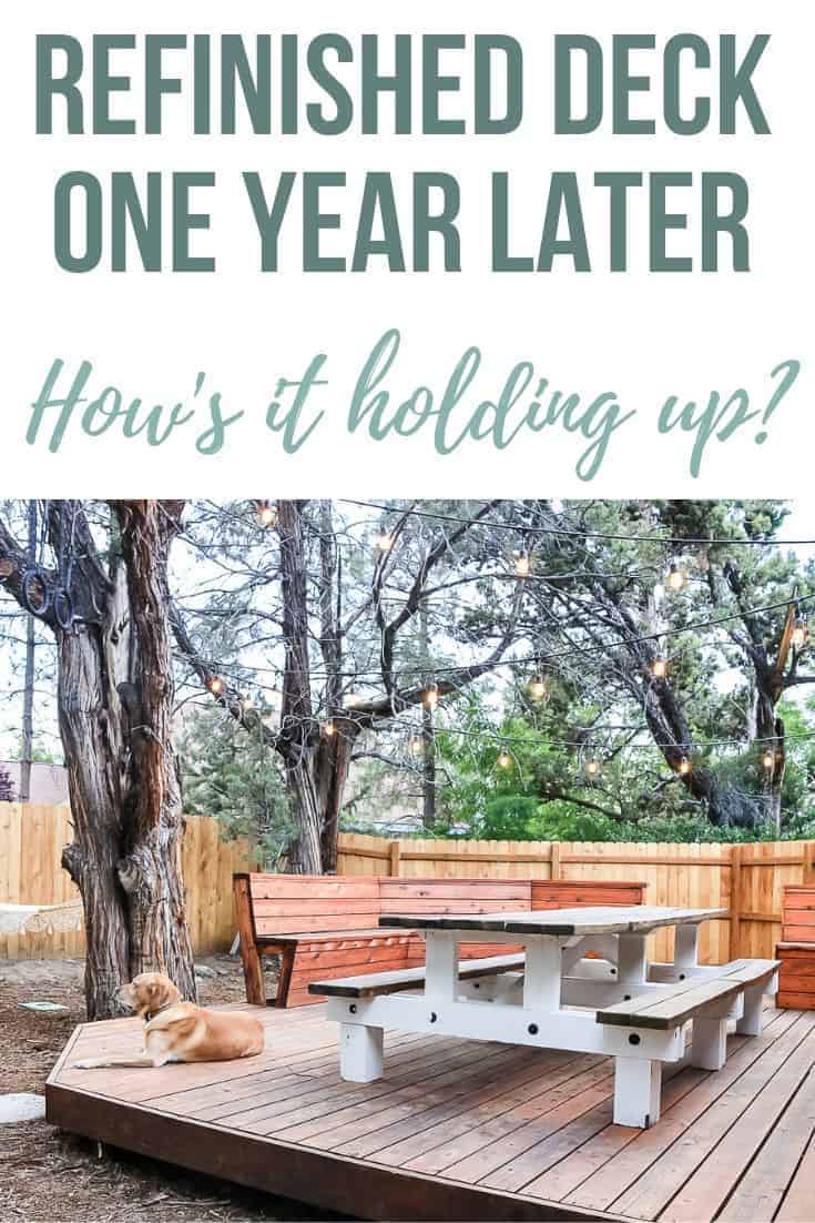 Full image of refinished deck with a dog sitting on the floor and outdoor lights lighting the place with text overlay that says Refinished Deck One Year Later How's It Holding Up?