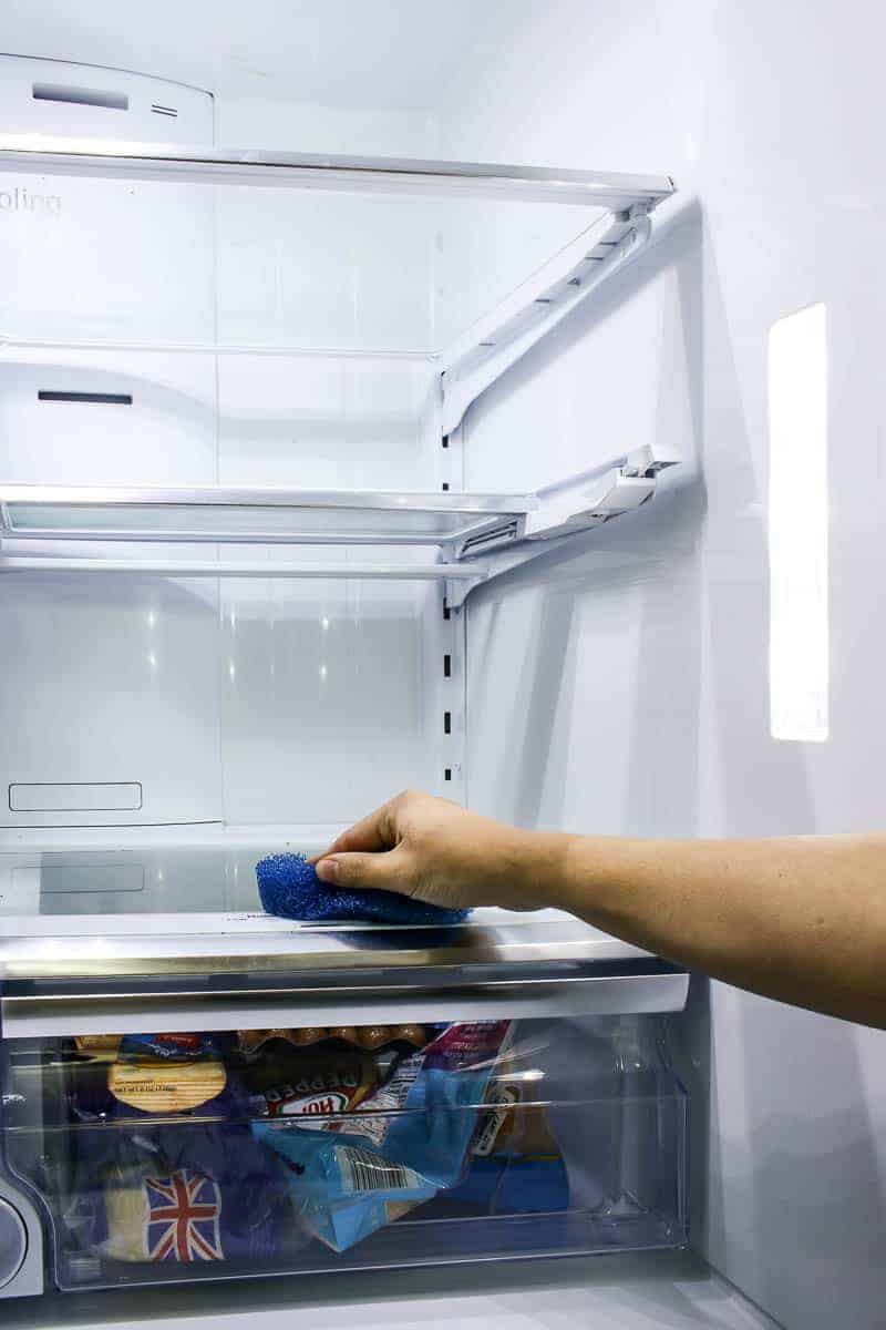 Refrigerator clean out by wiping out all the crumbs and mess off of the shelves