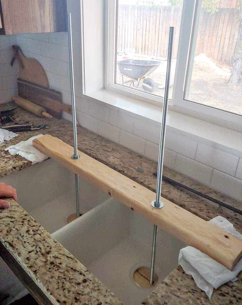 Two wooden boards holding up an undermount sink during the installation process