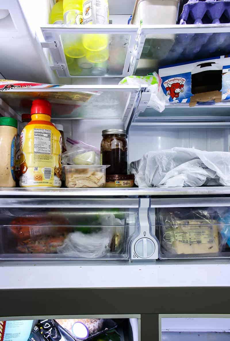Close up view inside of the messy refrigerator showing the dividers before cleaning