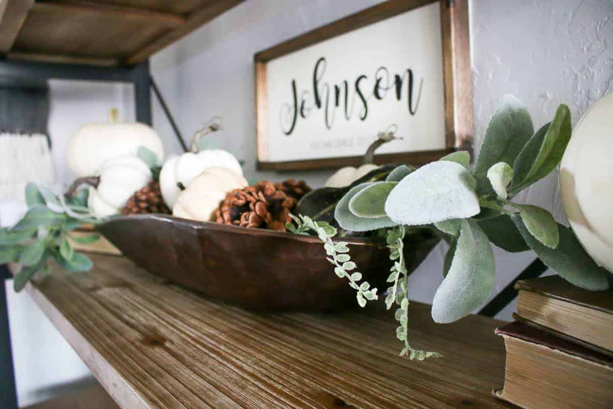 A closer look at the faux lambs ear greenery that sits in a vintage wood dough bowl with mini pumpkins and pinecones as part of my Fall themed living room shelf decor.