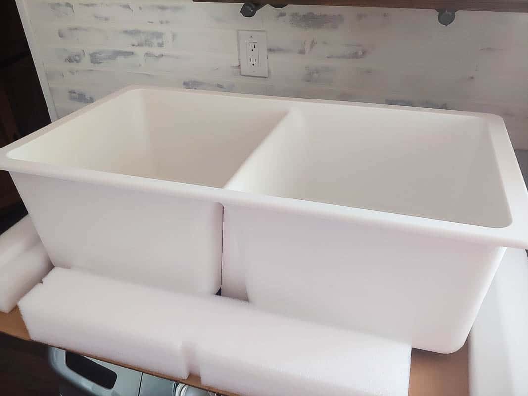 A large white farmhouse style undermount sink before installation