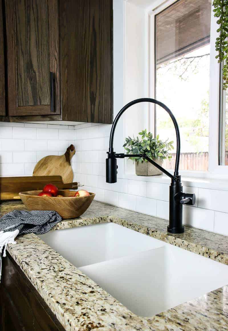 A closer look at the new undermounted kitchen sink with black faucet, installed in granite countertops for a farmhouse style kitchen